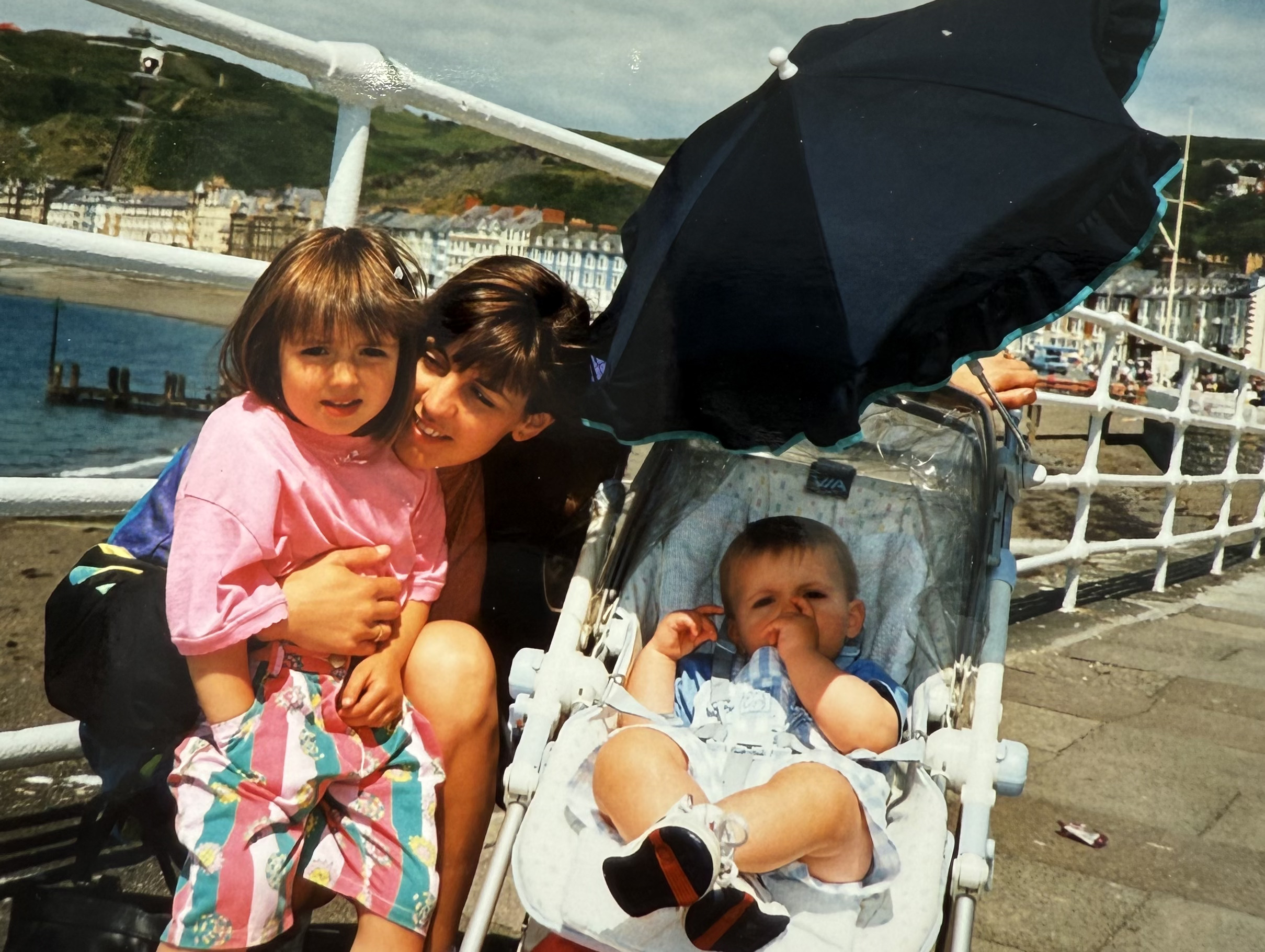 Young Rebecca with her mum and brother on a seaside promenade