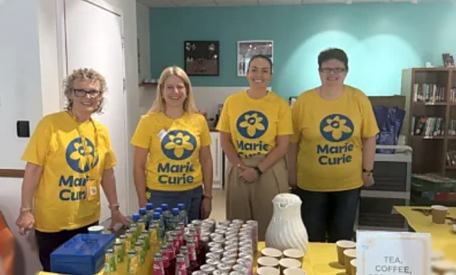 Rebecca and fellow volunteers in Marie Curie t-shirts behind a fundraising refreshment table