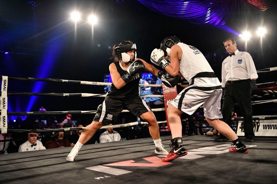Rebecca boxing in a match, throwing a punch at her opponent in the ring