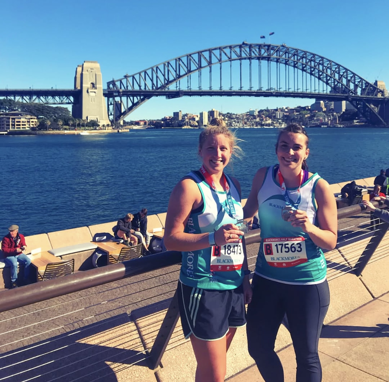 Rebecca and a friend with half-marathon medals in front of the Sydney Harbour Bridge