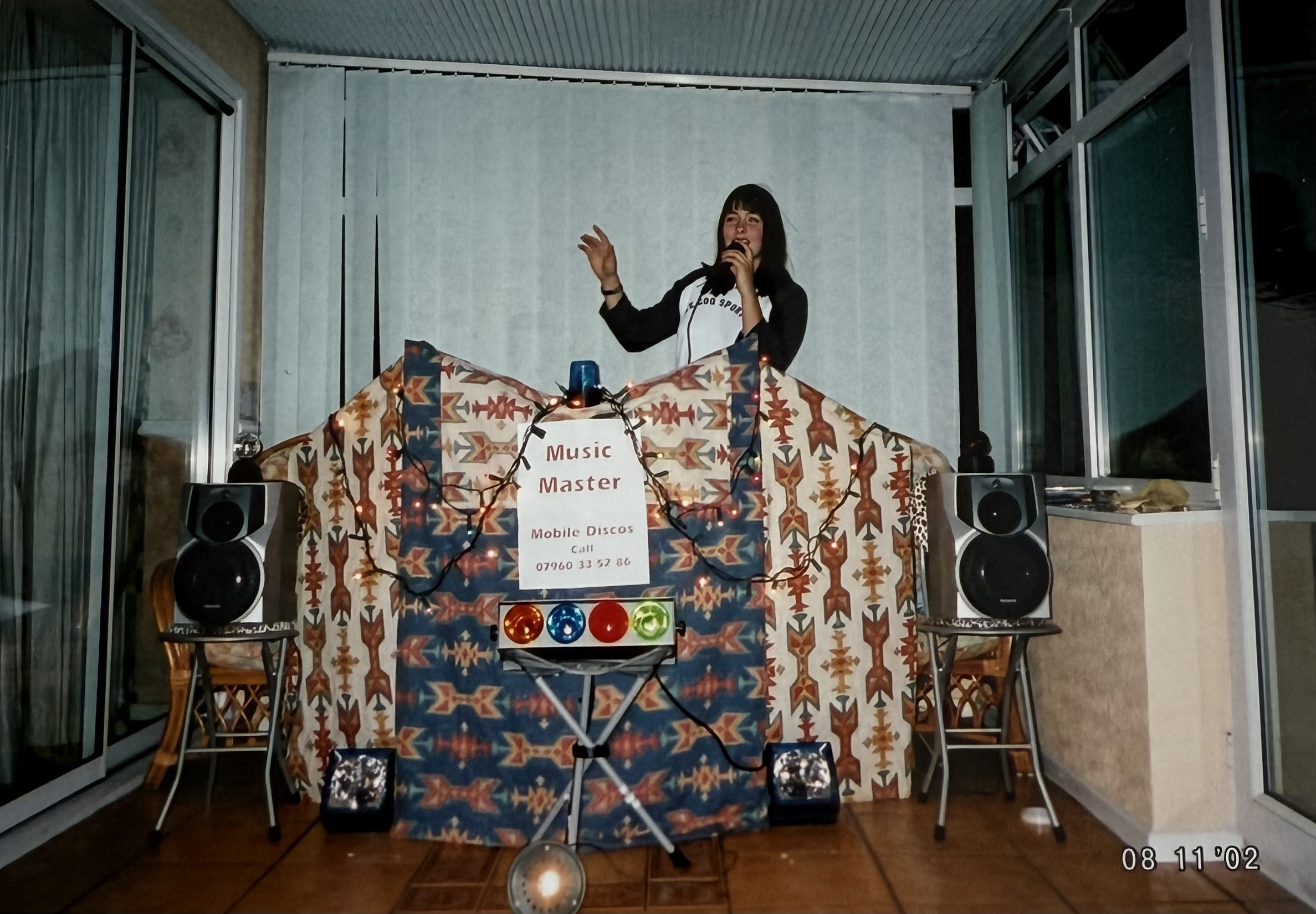 A teenage Rebecca with a microphone behind her first DJ booth