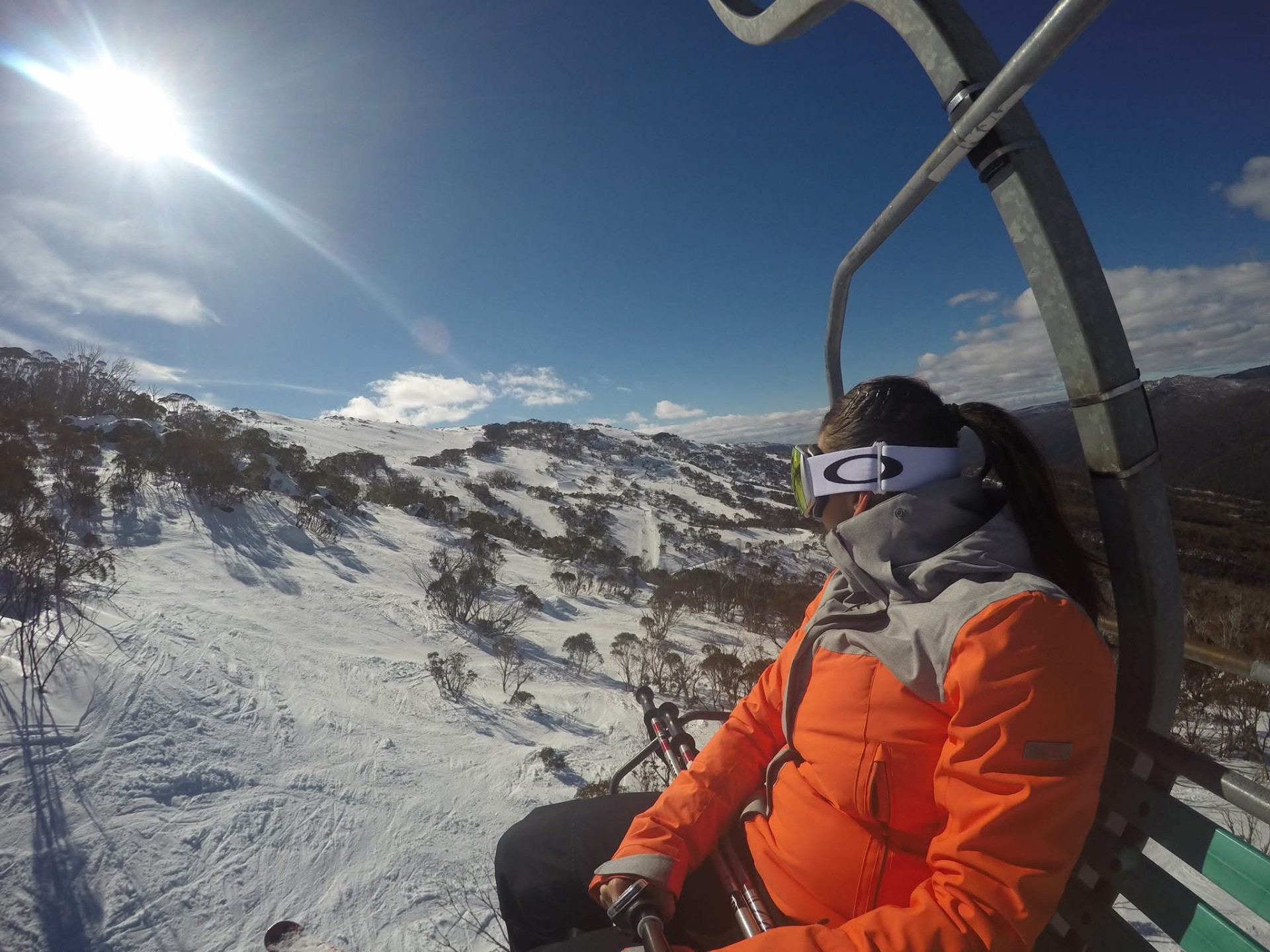 Rebecca in ski gear on a chairlift looking out over snow-covered mountains